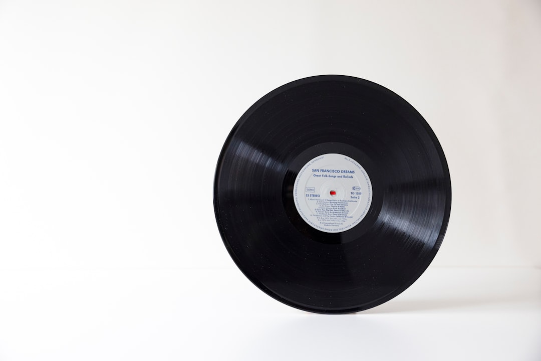 A black vinyl record with a central label on a white surface
